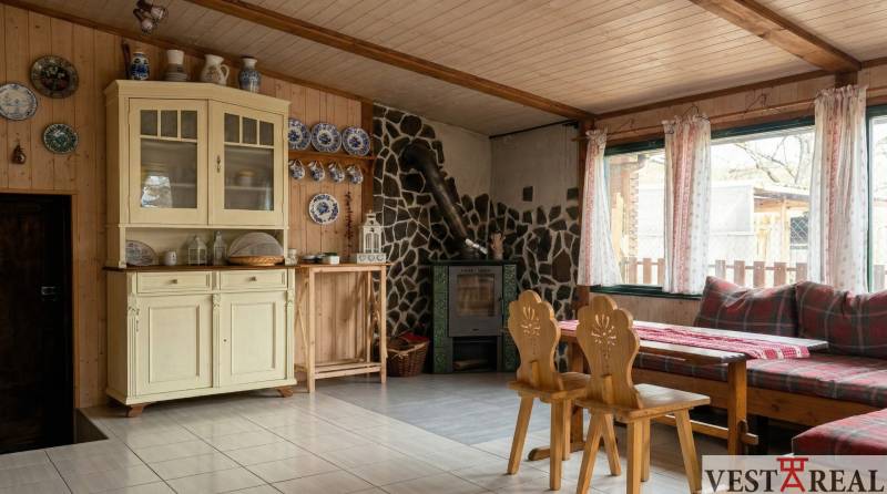 Vidět útulnou místnost s kamny, dřevěným obložením a nábytkem v 2-pokojovém bytě.