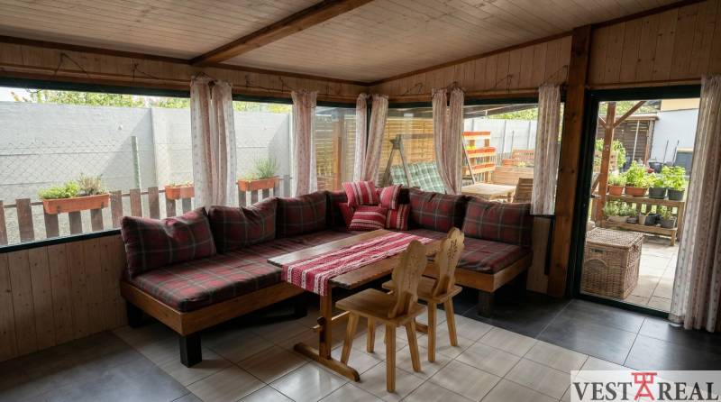 Útulný prostor s dřevěným dekorem, velkou pohovkou a jídelním stolem v 2-pokojovém bytě.