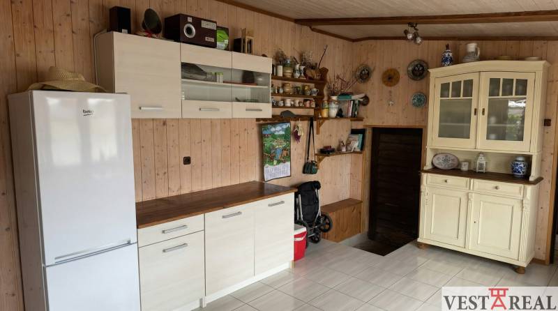 Kuchyně v 2-pokojovém bytě se světlým nábytkem, bílou lednicí a dekoracemi na stěně.