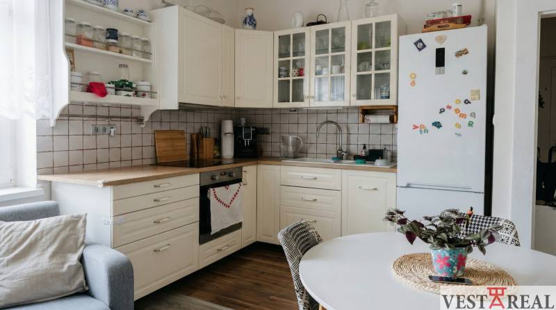 Kuchyně v 2-pokojovém bytě s bílým nábytkem a podlahou s dřevěným dekorem.