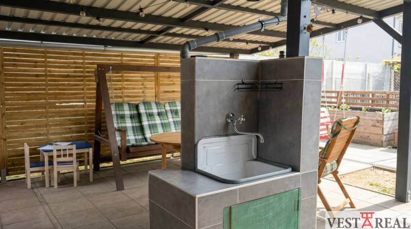 Zastřešená terasa na Coburgově ulici v Trnavě, s umyvadlem, houpačkou a dětským stolkem.