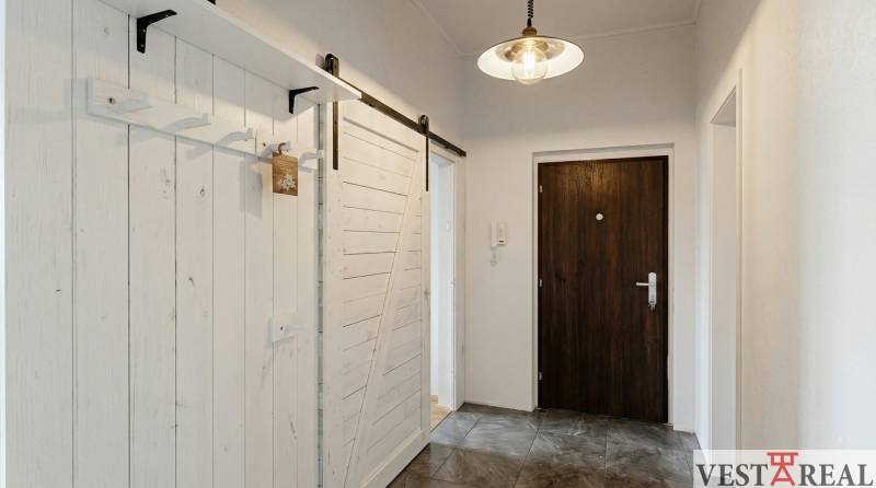 Chodba s šedou podlahou a bílými posuvnými dveřmi v 2pokojovém bytě.