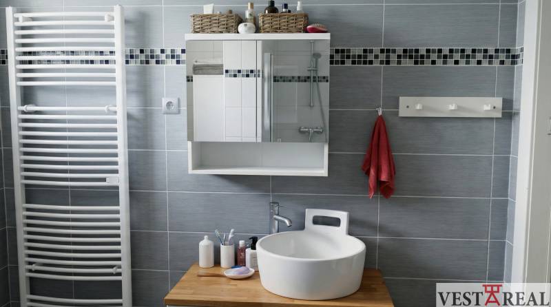 Koupelna v 2-pokojovém bytě s umyvadlem, zrcadlem a věšákem na ručníky.