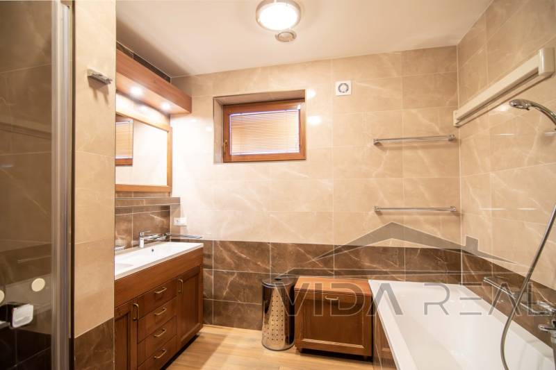 Koupelna v rodinném domě s vanou, umyvadlem, sprchovým koutem a podlahou s dřevěným dekorem.