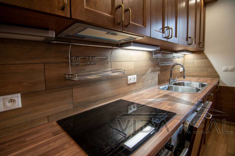 Kuchyně v rodinném domě s podlahou s dřevěným dekorem a kuchyňskou linkou ze dřeva.