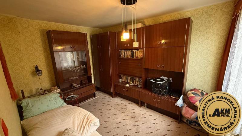 Pokoj v rodinném domě s nábytkem, postelí a vzorovanými tapetami na stěnách.