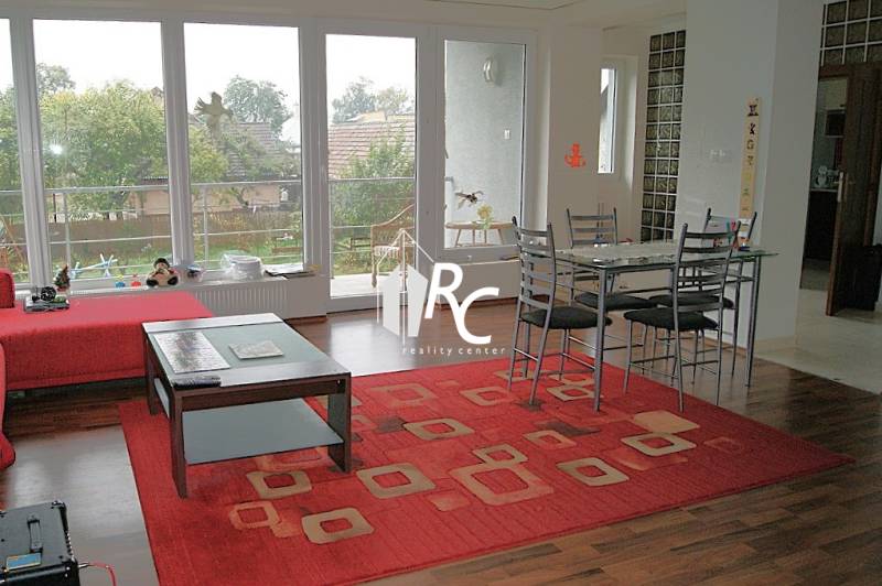 Obývací pokoj v rodinném domě s podlahou s dřevěným dekorem a červeným kobercem.