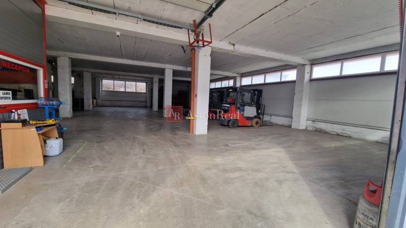 Interiéry skladů a hal s vysokými stropy a pracovními zařízeními, včetně vysokozdvižného vozíku.