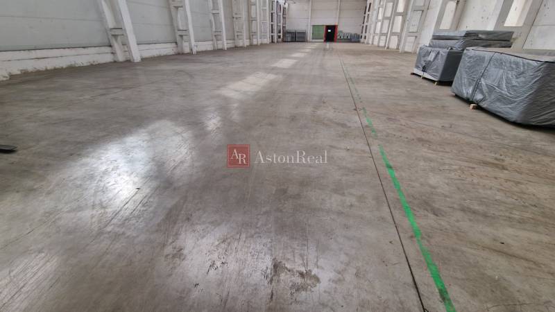 Prostorný interiér skladů a hal s betonovou podlahou a balíky na levé straně.