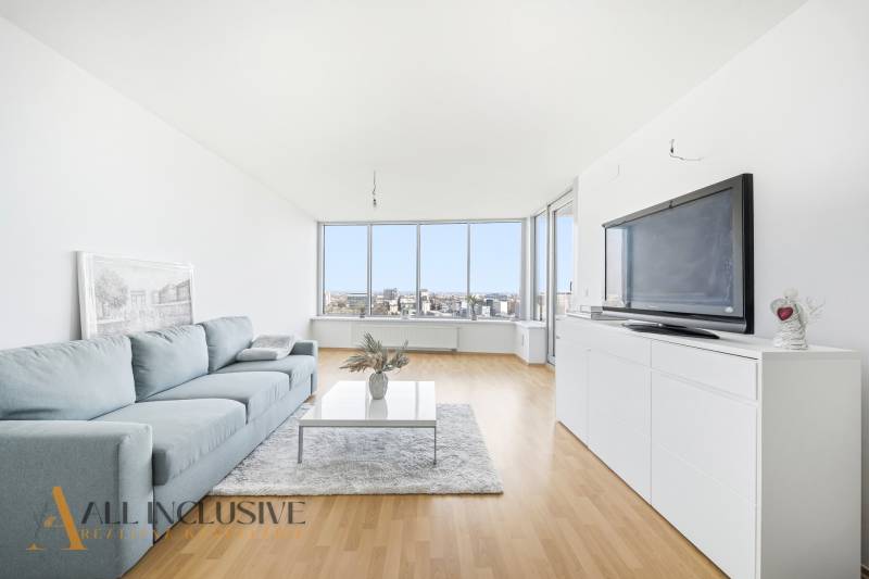 Obývací pokoj v dvoupokojovém bytě s pohovkou, televizí a podlahou s dřevěným dekorem.