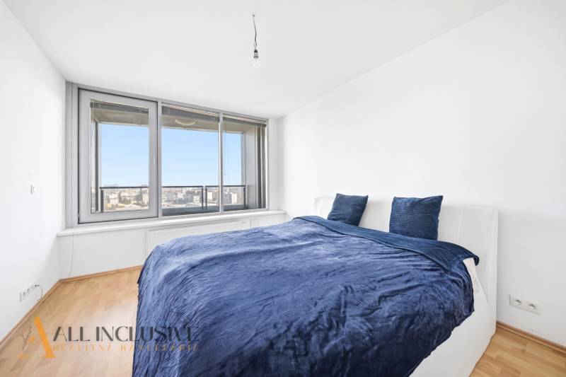 Ložnice v 2pokojovém bytě s postelí a velkým oknem, podlaha s dřevěným dekorem.