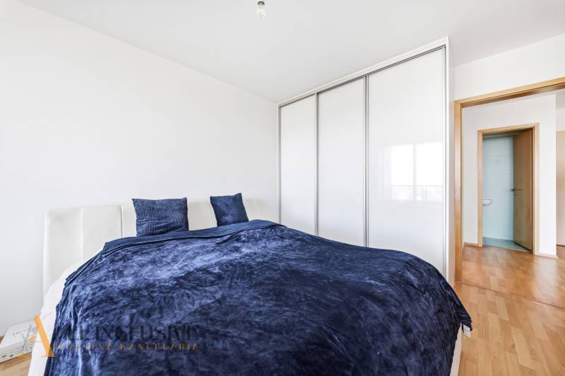 Ložnice v 2-pokojovém bytě s postelí, šatníkem a podlahou s dřevěným dekorem.