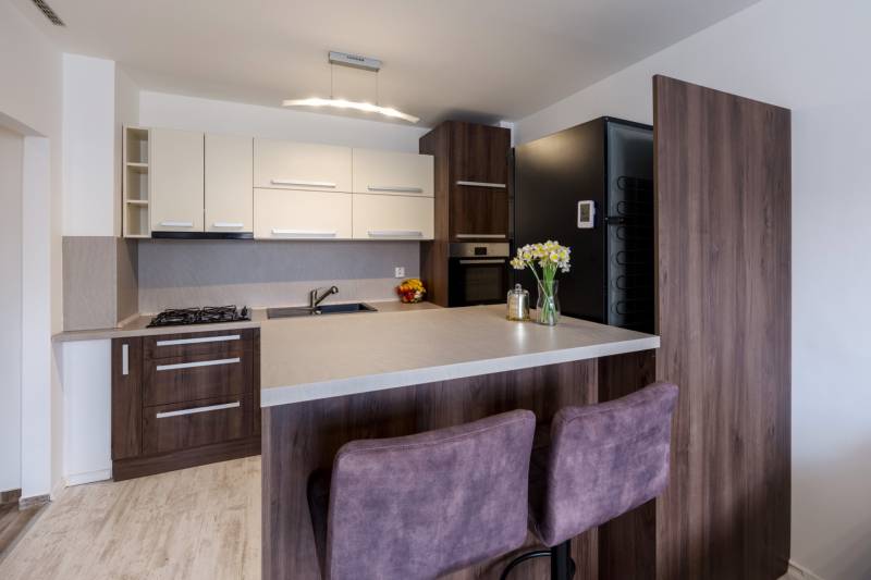 Kuchyně v 2-pokojovém bytě s barovým pultem, pult s podlahou s dřevěným dekorem, židle.