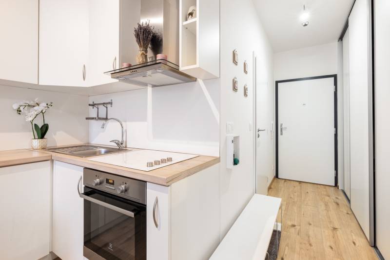 Světlá kuchyně s dřevěným dekorem v 1-pokojovém bytě, vstupní chodba.