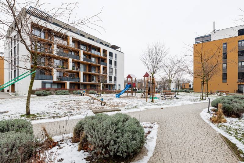 Bytový dům na Béžové ulici v Bratislavě - Petržalce s dětským hřištěm a zimní atmosférou.