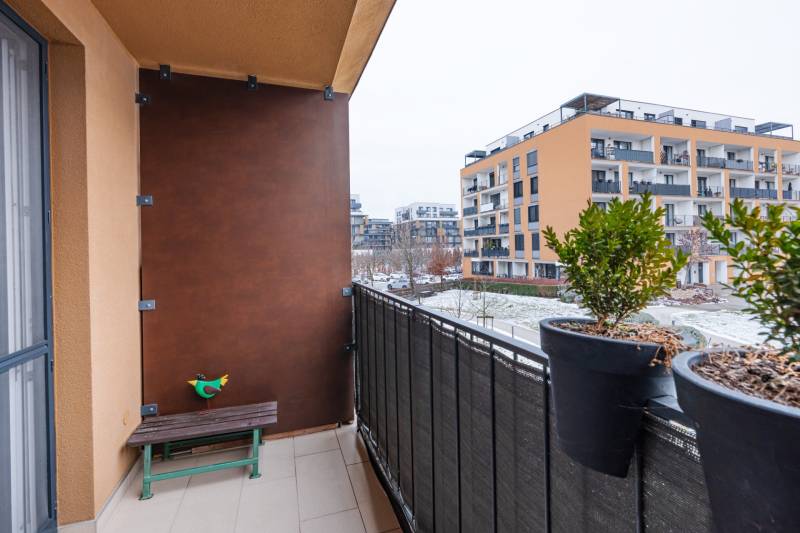 Balkon 1-pokojového bytu na Béžové ulici v Bratislavě - Petržalce se zelení a lavičkou.