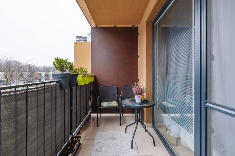 Balkon v 1-pokojovém bytě na Béžové ulici v Bratislavě - Petržalce s rostlinami a nábytkem.