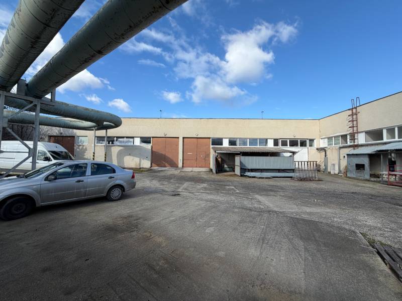 Sklady a haly v Nových Zámcích na ulici Nové Zámky s průmyslovým komplexem a auty.