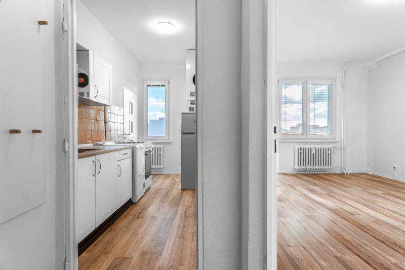 Svetlá kuchyňa a obývacia izba s podlahou s dreveným dekorom v 1-izbovom byte.