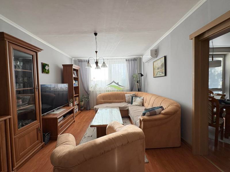 Obývací pokoj s pohodlnou sedačkou, podlahou s dřevěným dekorem a příjemným osvětlením ve 3-pokojovém bytě.