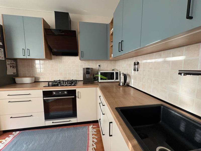 Kuchyňská linka v 3-pokojovém bytě s podlahou s dřevěným dekorem a spotřebiči.