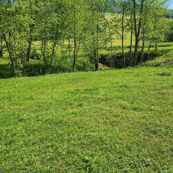 Zelený travnatý pozemek se třemi stromy na pozemku pro bydlení v ulici Vyšné Malatiny.