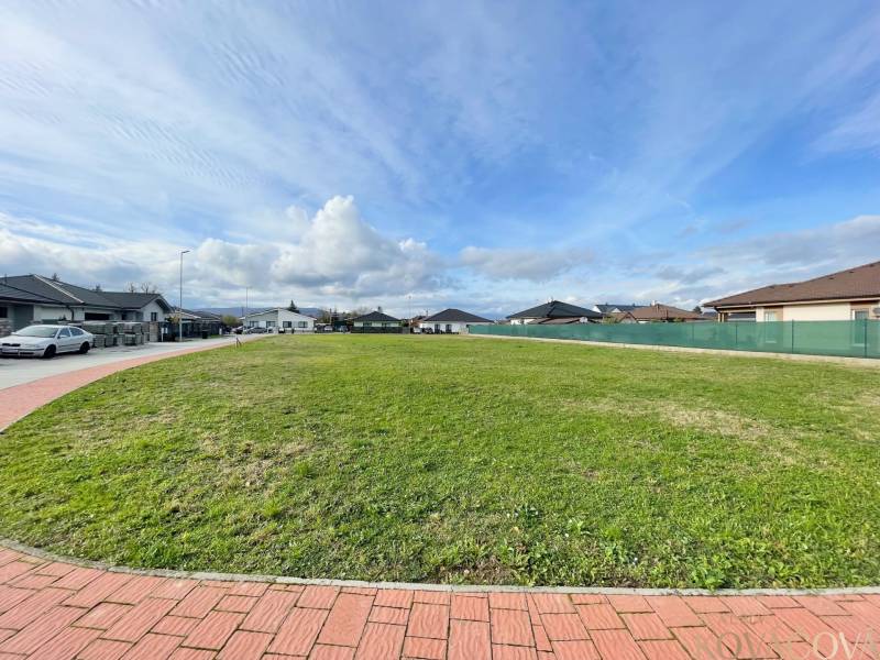 Pohled na prostorný stavební pozemek v Kočovcích, obklopený rodinnými domy.