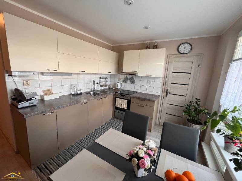 Kuchyně v 3-pokojovém bytě se světlými skříňkami a jídelním stolem.