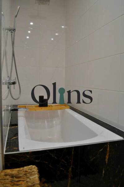 Koupelna v 3-pokojovém bytě s vanou, sprchovou hlavicí a bílými obklady.