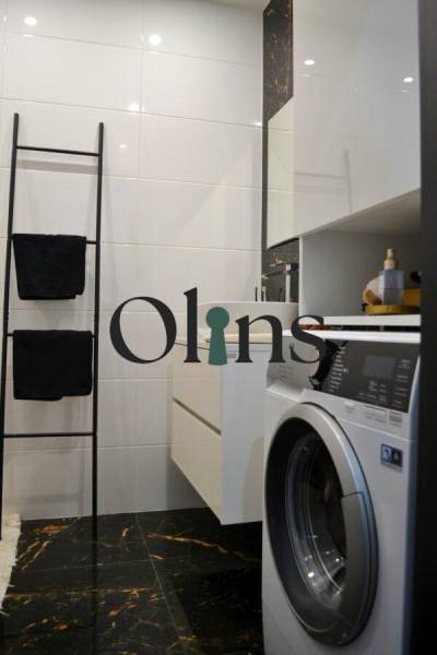 Koupelna v 3-pokojovém bytě s pračkou, žebříkovým držákem na ručníky a bílými stěnami.