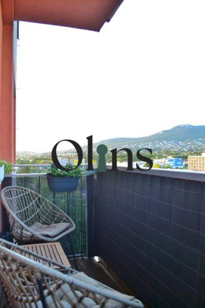 Balkon s ratanovými křesly a výhledem na zeleň ve 3-pokojovém bytě.