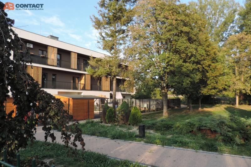 Bytový dům na ulici Bodona, obklopený zelení a stromy, ideální pro bydlení v garsonce.