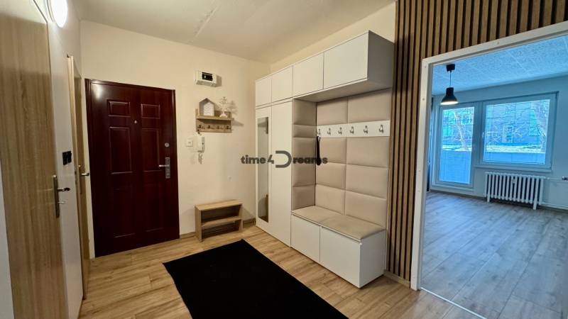 Chodba s věšákovou stěnou, zrcadlem a vstupem do obývací části, 3-pokojový byt.