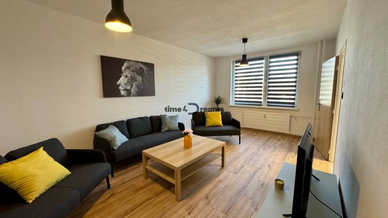 Obývací pokoj s podlahou s dřevěným dekorem, sedačka, konferenční stolek, obraz lva.