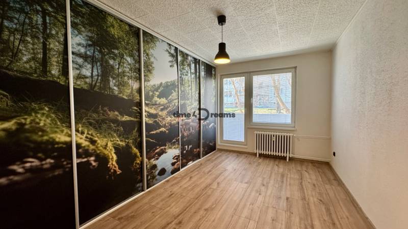 Pokoj v 3-pokojovém bytě s velkoplošnou tapetou lesa a podlahou s dřevěným dekorem.