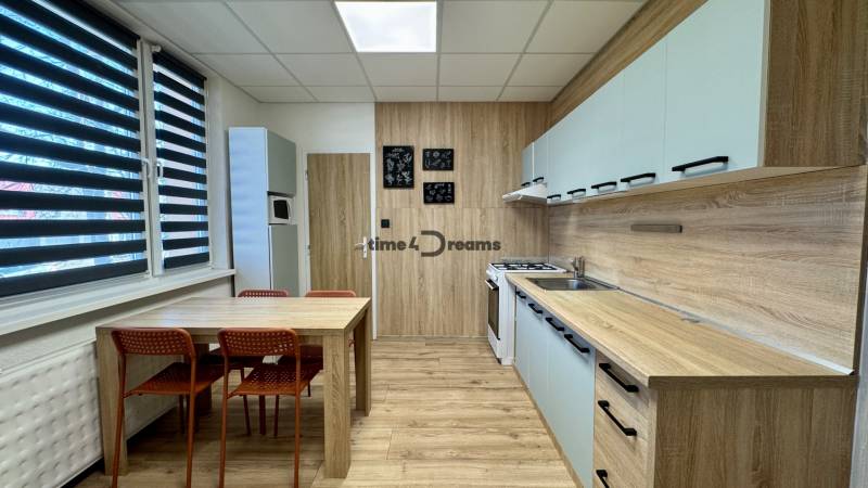 Kuchyně ve 3-pokojovém bytě s jídelním stolem a podlahou s dřevěným dekorem.