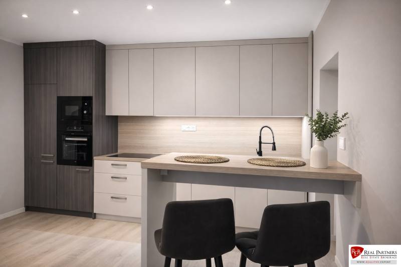 Kuchyně v 2-pokojovém bytě s podlahou s dřevěným dekorem, moderní linkou a jídelním stolem.