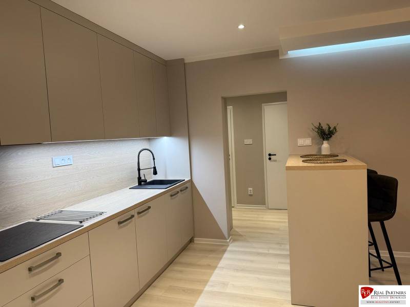 Kuchyně v 2-pokojovém bytě s podlahou s dřevěným dekorem a linkou.