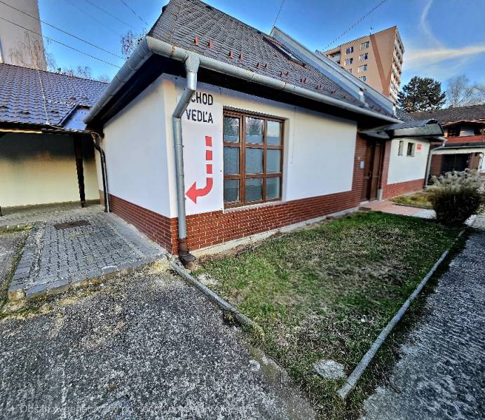 Budova s cihlovým obkladem v Bánovcích nad Bebravou, označení vchodu vedle.