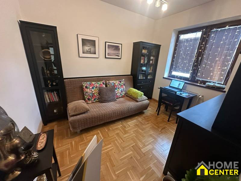 Obývací pokoj s pohovkou a pracovním stolem v rodinném domě s podlahou s dřevěným dekorem.