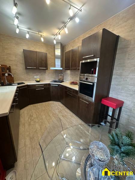 Kuchyně v rodinném domě s dřevěným dekorem podlahy a bohatým osvětlením.