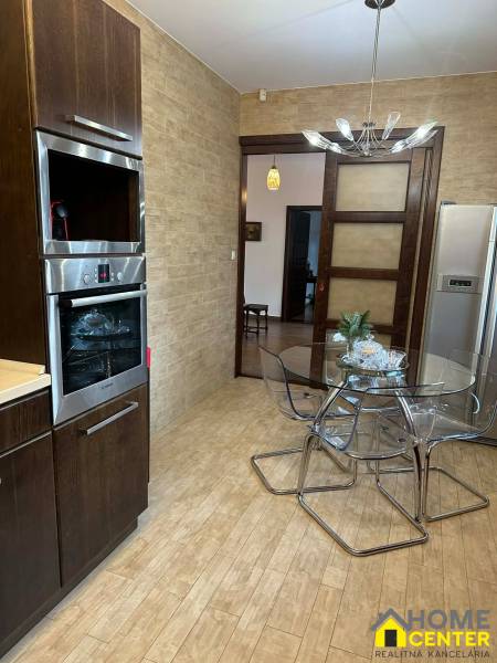 Kuchyně v rodinném domě s podlahou s dřevěným dekorem a skleněným stolem.