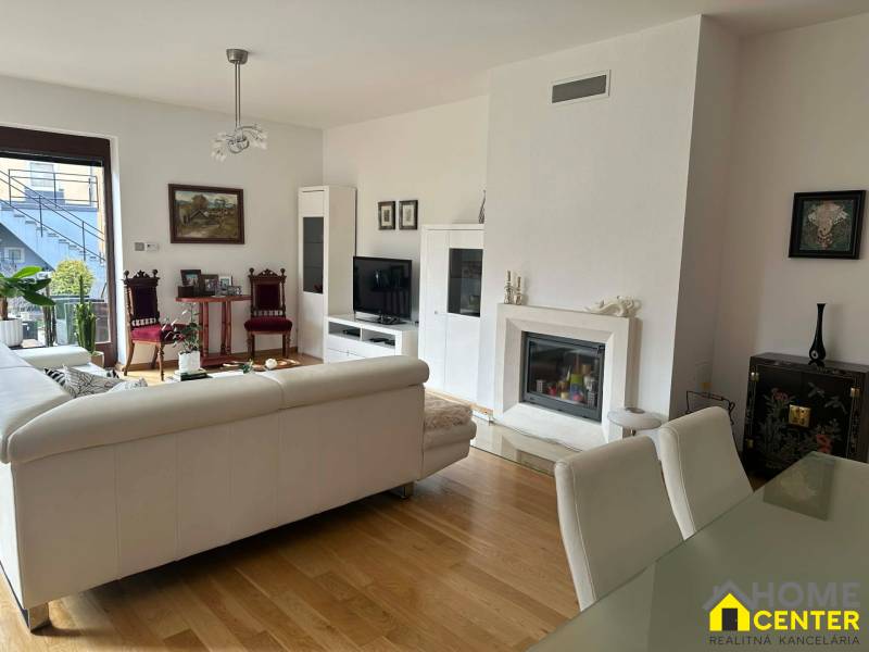 Interiér rodinného domu s krbem, pohovkou a podlahou s dřevěným dekorem.