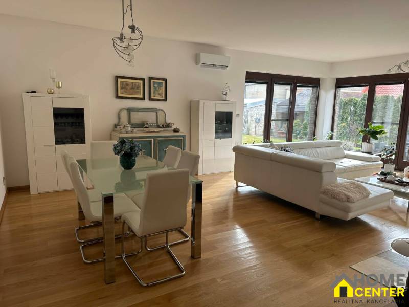 Obývací pokoj v rodinném domě s podlahou s dřevěným dekorem a bílým nábytkem.