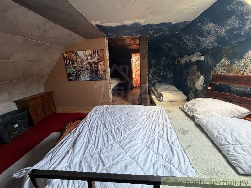 Podkrovní ložnice v rodinném domě s obrazem a modrou stěnou plnou vzorů.