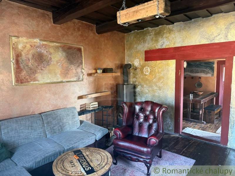 Obývací pokoj v rodinném domě s koženým křeslem a kachlovými kamny.