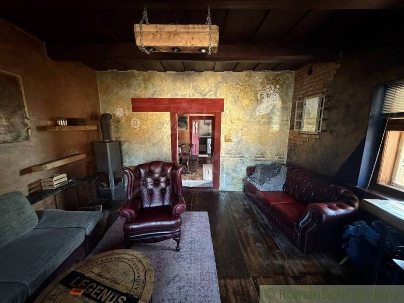 Rustikální obývací pokoj v rodinném domě s koženými křesly a podlahou s dřevěným dekorem.