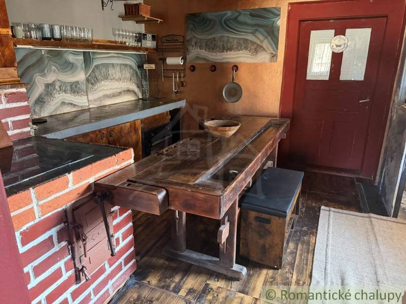 Rustikální kuchyně v rodinném domě s cihlovými detaily a podlahou s dřevěným dekorem.