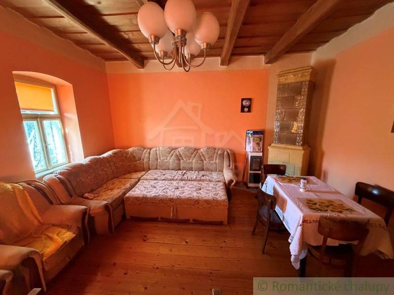 Obývací pokoj s rohovou sedačkou, podlahou s dřevěným dekorem a kachlovými kamny v rodinném domě.