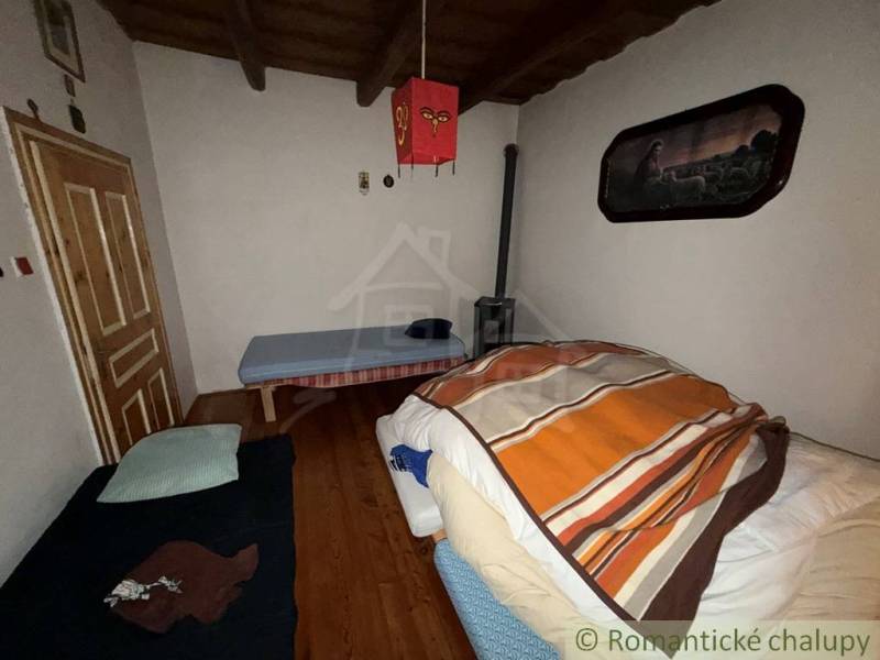 Pokoj v rodinném domě s dřevěným dekorem podlahy a jednoduchým zařízením.